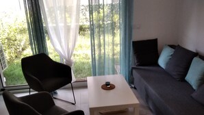 Ein modernes Wohnzimmer mit einem schwarzen Sessel, einem weißen Tisch und einem grauen Sofa mit türkisfarbenen Kissen.