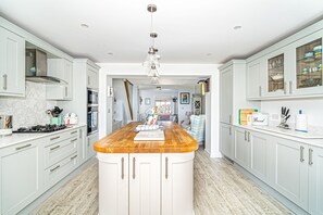 A modern kitchen with a central island, stainless steel appliances, and light grey cabinetry.