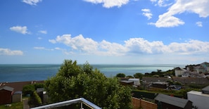 Zona residencial costera con casas, cielo despejado y vista al mar.