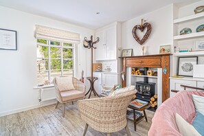 Una sala de estar acogedora con chimenea, muebles de mimbre y vistas al exterior.