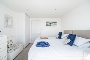 A bedroom with a bed, a dresser, a mirror, a door, and a wall-mounted picture.