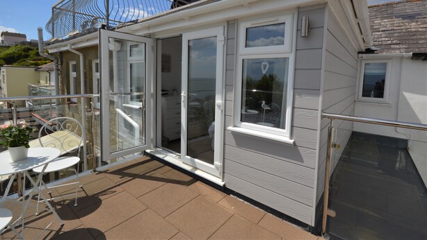 A small, single-story house with a patio area, a sliding glass door, and a small balcony. - Jan Dee Cottage -  a cottage that sleeps 6 guests  in 3 bedrooms (Ventnor)