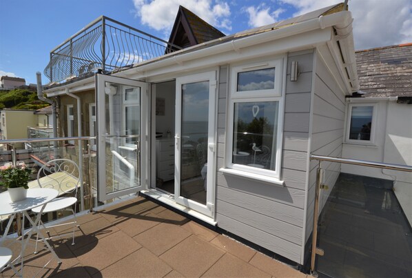 Une petite maison de plain-pied avec un patio, une porte-fenêtre coulissante et un petit balcon.