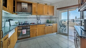 Una cocina moderna con armarios de madera, una estufa de acero inoxidable y un amplio ventanal con vistas a un balcón.