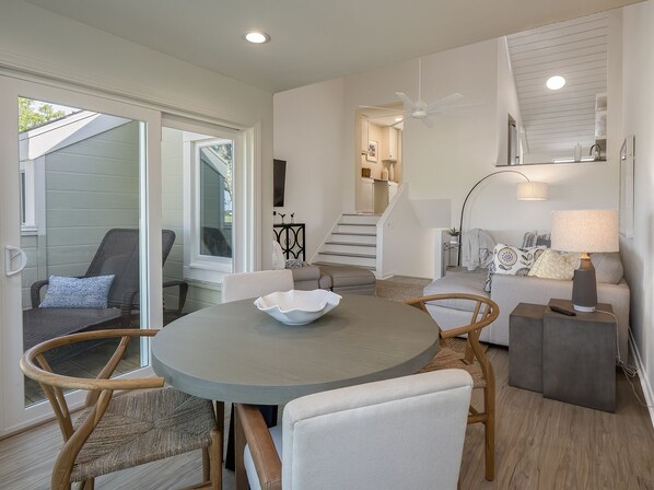 A modern living room with a round table, two chairs, a sofa, and a lamp.