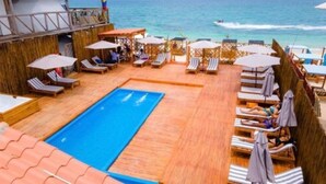 A pool area with lounge chairs and umbrellas, overlooking the sea. - Cabana Glamping Geronimo  (Cartagena)
