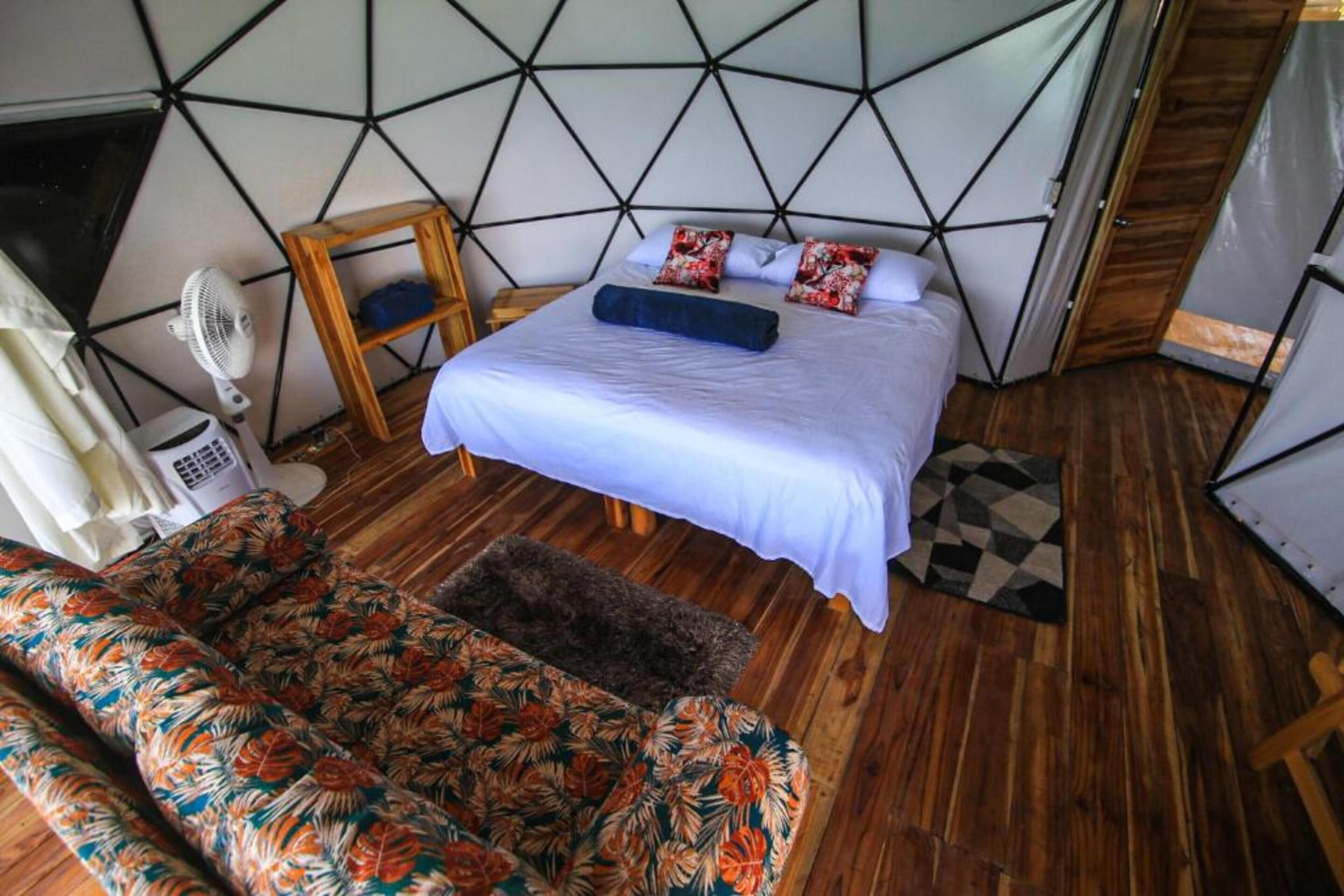 Une chambre à coucher avec un lit, un plancher en bois, un canapé à motifs et un motif géométrique sur le mur.