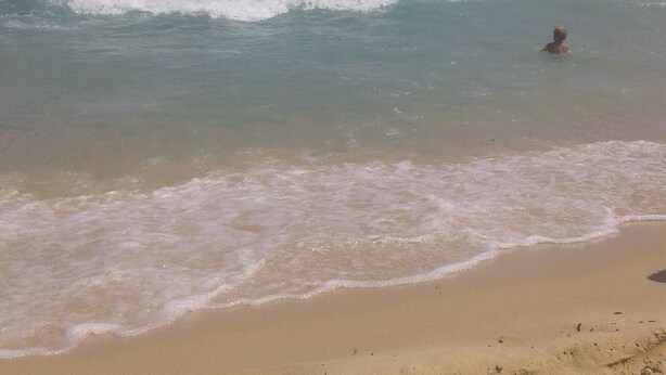 A beach with clear water, waves, and a sandy shore. - we think of the holidays (VILLASIMIUS)