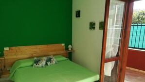A room with a wooden bed, green walls, and a glass door leading to an outdoor area. - we think of the holidays (VILLASIMIUS)