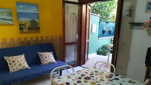 A room with a blue sofa, a table with a fruit and spice pattern, and a view of a garden through a door. - we think of the holidays (VILLASIMIUS)