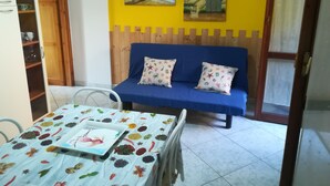 A room with a blue sofa, two cushions, a table with a colorful tablecloth, and two paintings on the wall. - we think of the holidays (VILLASIMIUS)