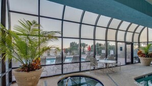 Ein Poolbereich im Innenbereich mit Glasverkleidung, Liegestühlen und einem Whirlpool.