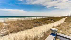 Ein Sandweg am Strand, mit einer Holzzahlung und freiem Blick auf das Meer.