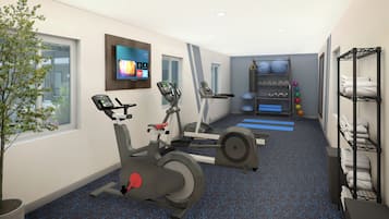 A modern gym with stationary bikes, a treadmill, and a wall-mounted TV displaying fitness programs.