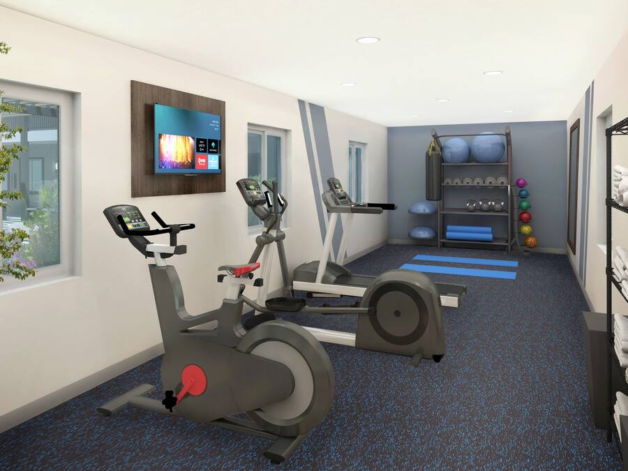 A modern gym with stationary bikes, a treadmill, and a wall-mounted TV displaying fitness programs.