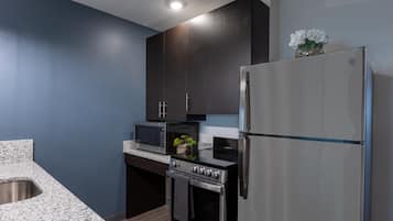 Eine moderne Küche mit dunklen Schränken, einem Edelstahl-Kühlschrank, einer Mikrowelle und einem Backofen.