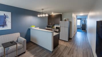 A compact kitchen with a central island, a microwave, a refrigerator, and a dining area with a sofa and a small table.