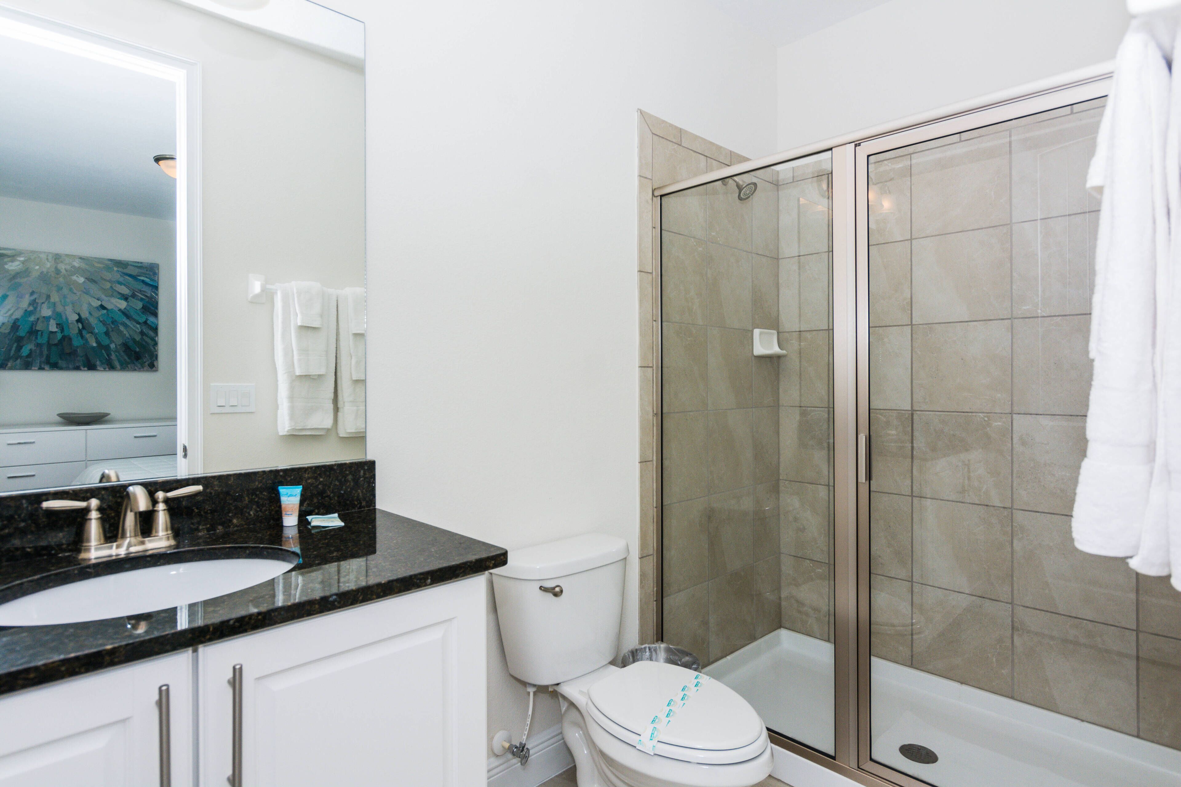 Une salle de bain équipée d’un lavabo, de toilettes et d’une douche à parois de verre.