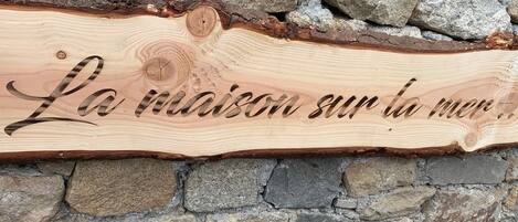 A wooden sign with carved text against a stone wall.