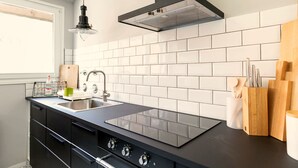 Una cocina moderna con encimera negra, salpicadero blanco de azulejos y un lavabo de acero inoxidable.