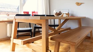 Una mesa de madera para comer con bancos, un radiador y una decoración de pájaro colgada en la pared.