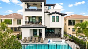 A modern two-story house with a swimming pool, outdoor seating, and a covered patio. - Games Room | Theater Room | Kids Themed Bedrooms | Private Pool (Kissimmee)