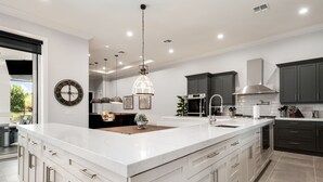 A modern kitchen with a large island, stainless steel appliances, and dark cabinetry. - Games Room | Theater Room | Kids Themed Bedrooms | Private Pool (Kissimmee)
