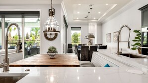 A modern kitchen with a marble countertop, stainless steel appliances, and pendant lighting. - Games Room | Theater Room | Kids Themed Bedrooms | Private Pool (Kissimmee)