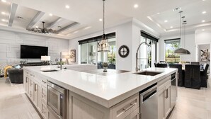 A modern kitchen with a large island, stainless steel appliances, and a dining area with a large table and chairs. - Games Room | Theater Room | Kids Themed Bedrooms | Private Pool (Kissimmee)