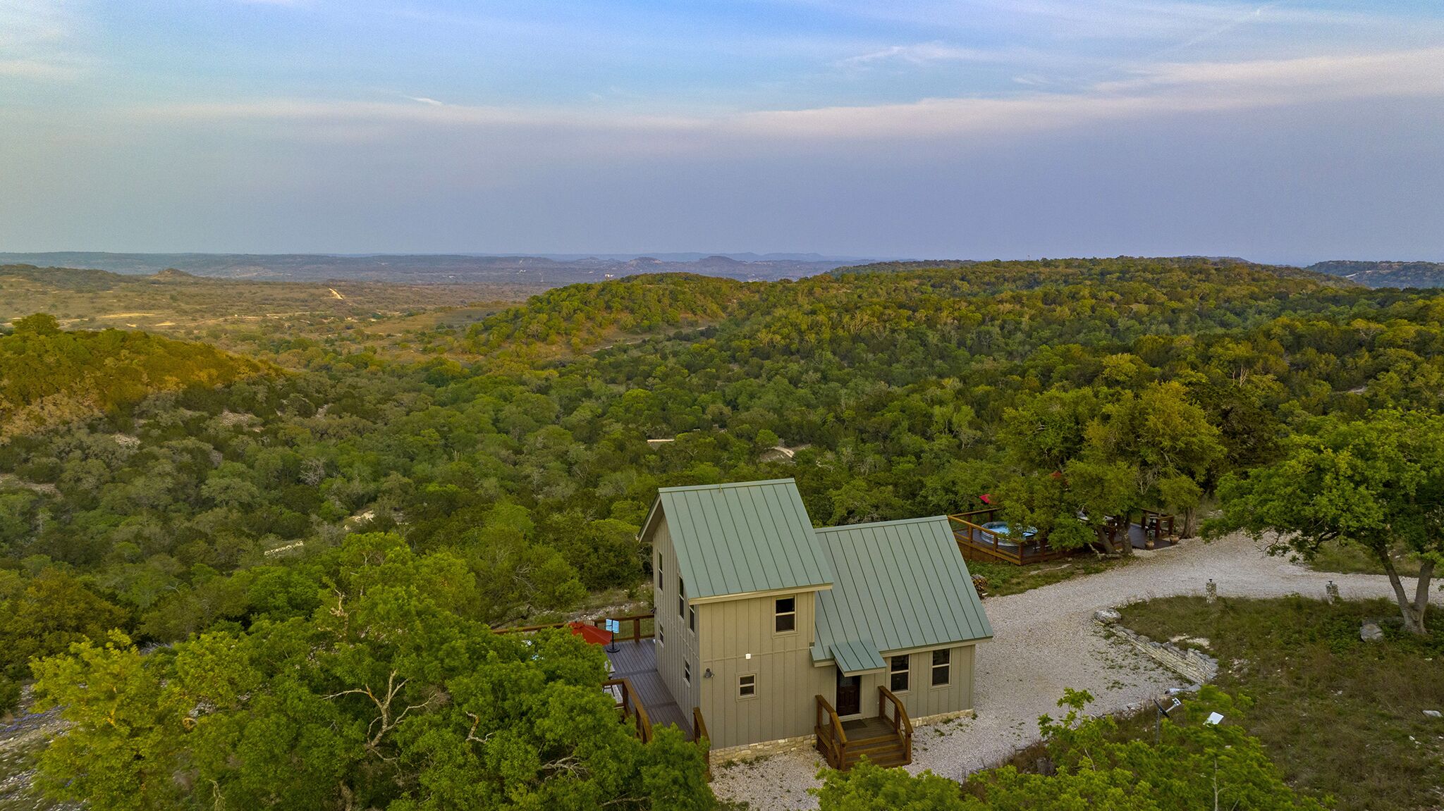 A small cabin with a green roof surrounded by dense forest, offering a panoramic view of the landscape.