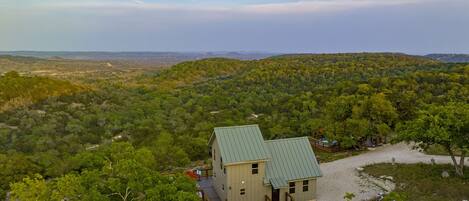 A small cabin with a green roof surrounded by dense forest, offering a panoramic view of the landscape.