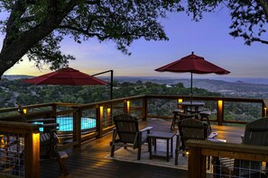 Relax on the deck with a view of the pool and surrounding landscape, surrounded by comfortable seating and shade.