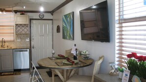Un comedor con una mesa redonda, sillas, una pequeña cocina con lavavajillas y una puerta.
