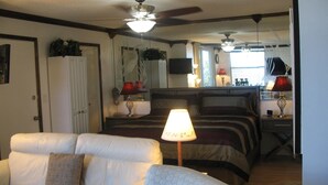 Una habitación de hotel con cama, sofá, escritorio y ventilador de techo.