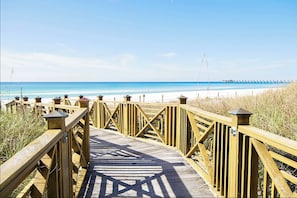 A wooden boardwalk leading to a beach with clear skies.