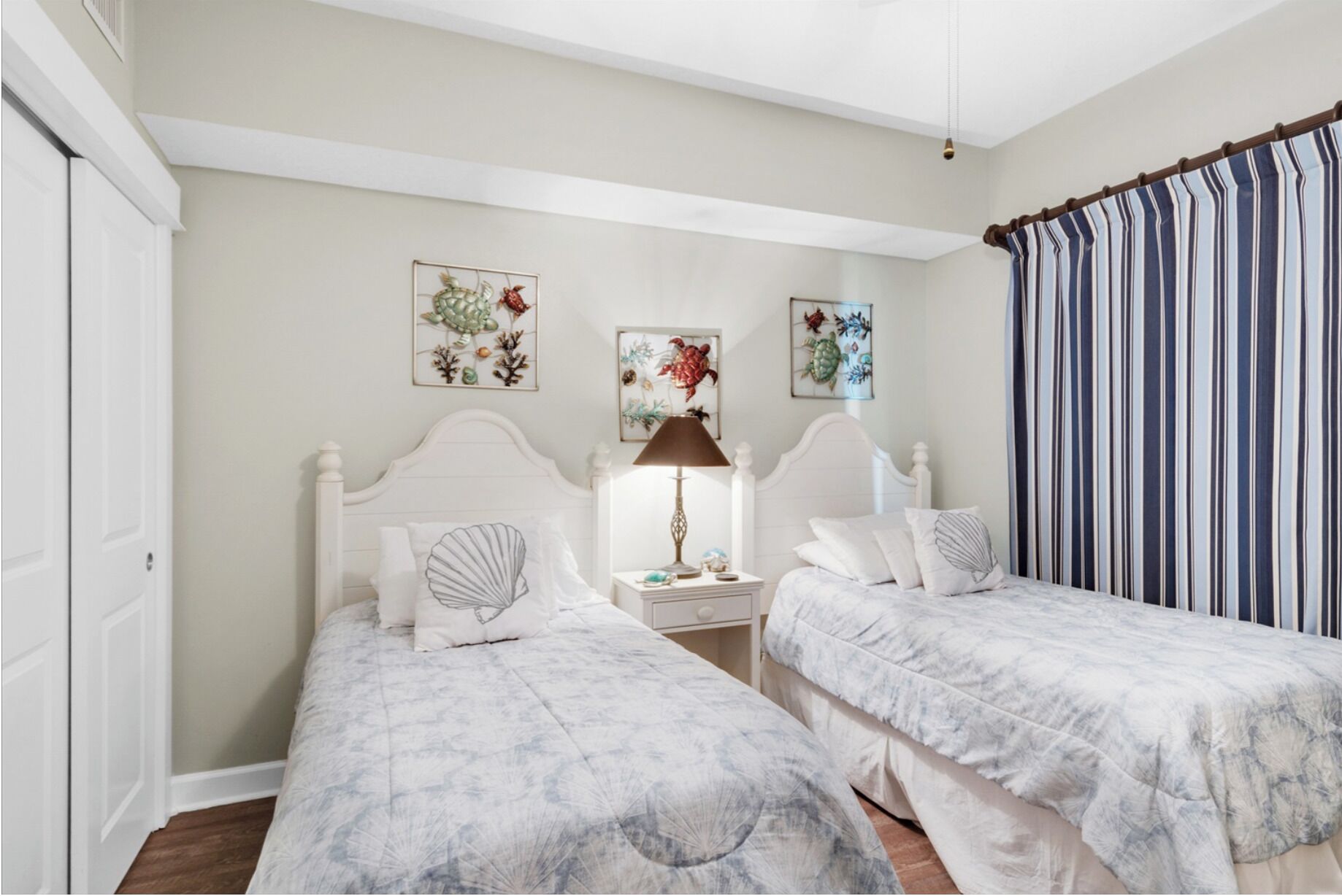 Une chambre avec deux lits, une table de chevet, une lampe et des œuvres d’art murales.