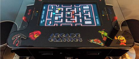 A retro arcade machine with a maze game, labeled 'Arcade Classics,' featuring characters from various games.