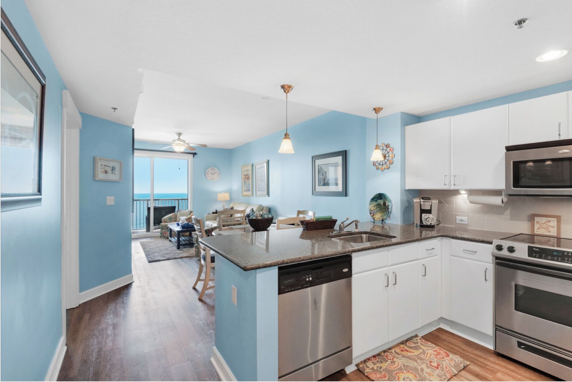 A modern kitchen with stainless steel appliances, a dining area with a view, and a living room with a ceiling fan.