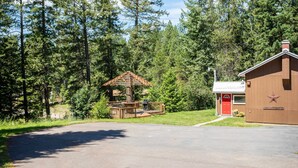Eine Lodge mit roter Tür, einer Holzterrasse und einem großen Baum im Hintergrund.