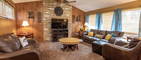A cozy living room with a fireplace, leather sofas, a coffee table, and a television.