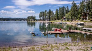 Ein Steg am See mit einem kleinen Boot, einer Holzpier und einem roten Stuhl.