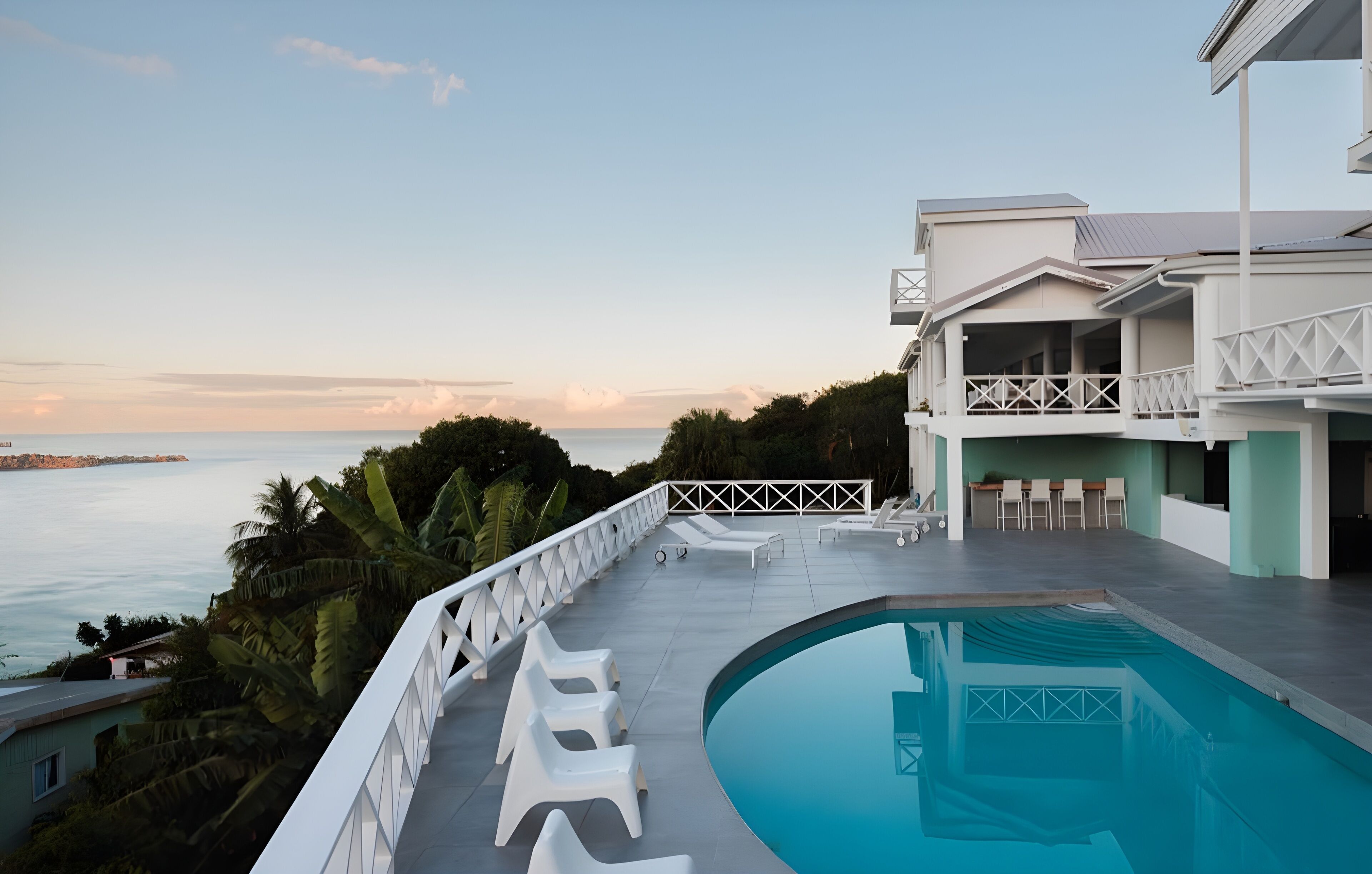A modern pool area with lounge chairs and a view of the sea.