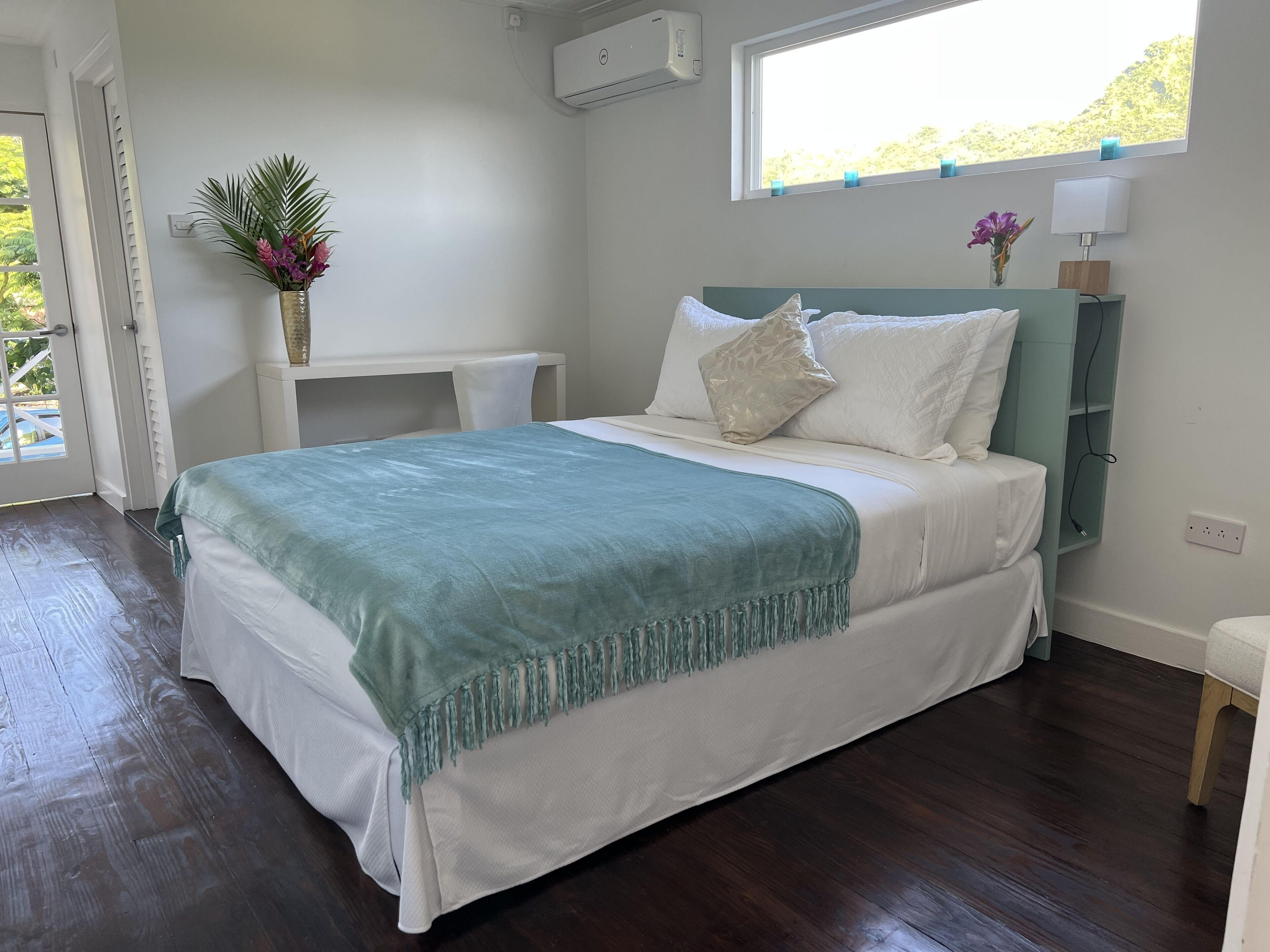 A bedroom with a bed, a desk, and a window.