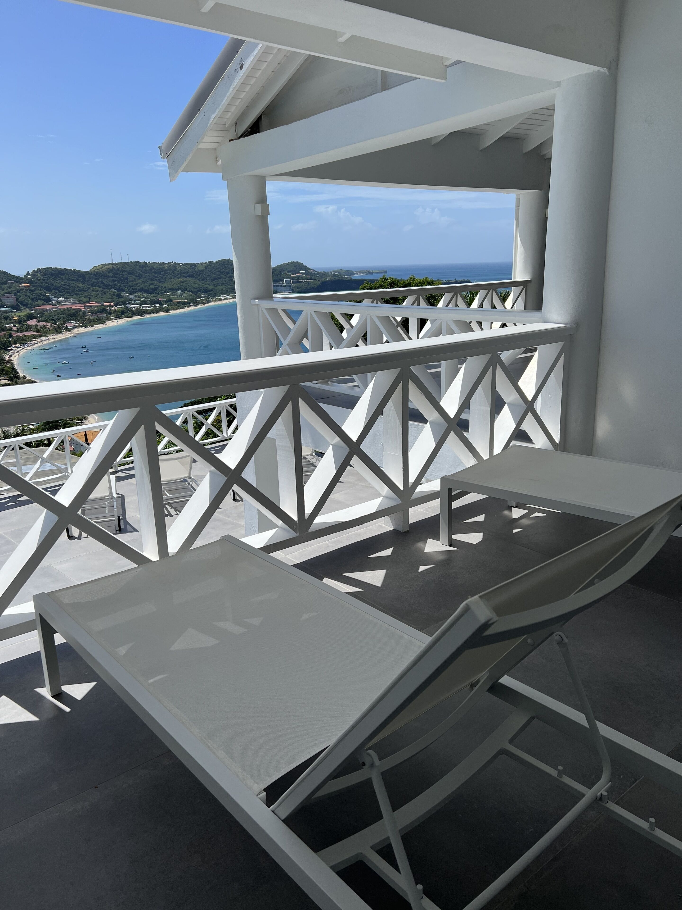 A balcony with a white railing, a table, and a chair.