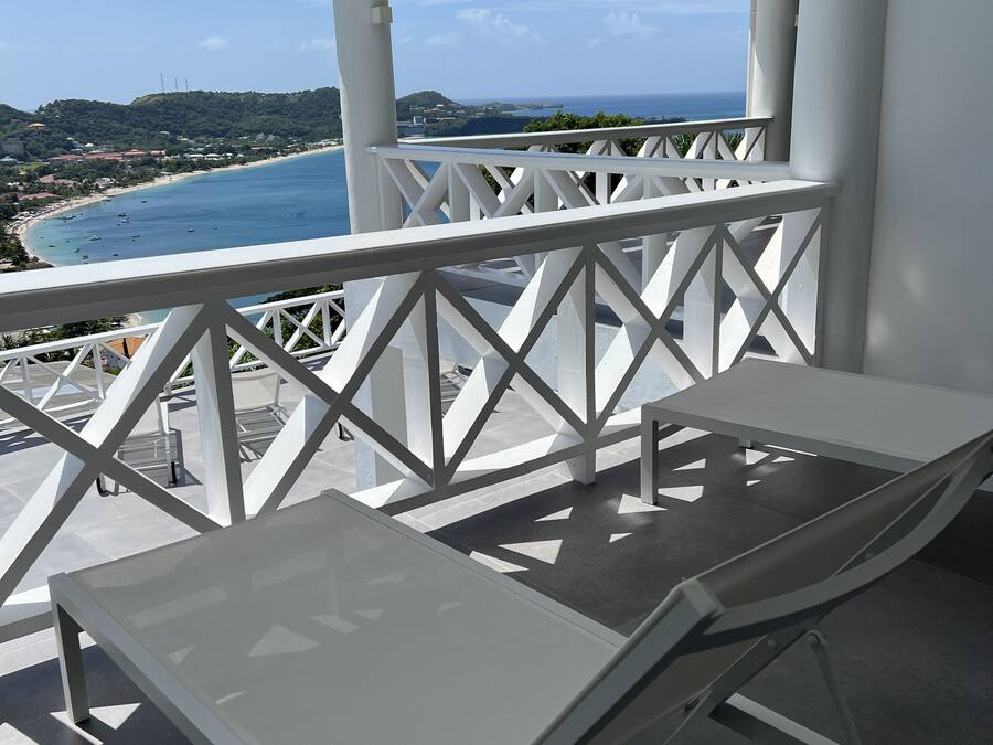 A balcony with a white railing, a table, and a chair.