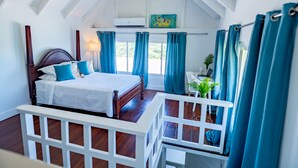 Un dormitorio con una cama de madera, cortinas azules, cabecera blanca y un tragaluz.