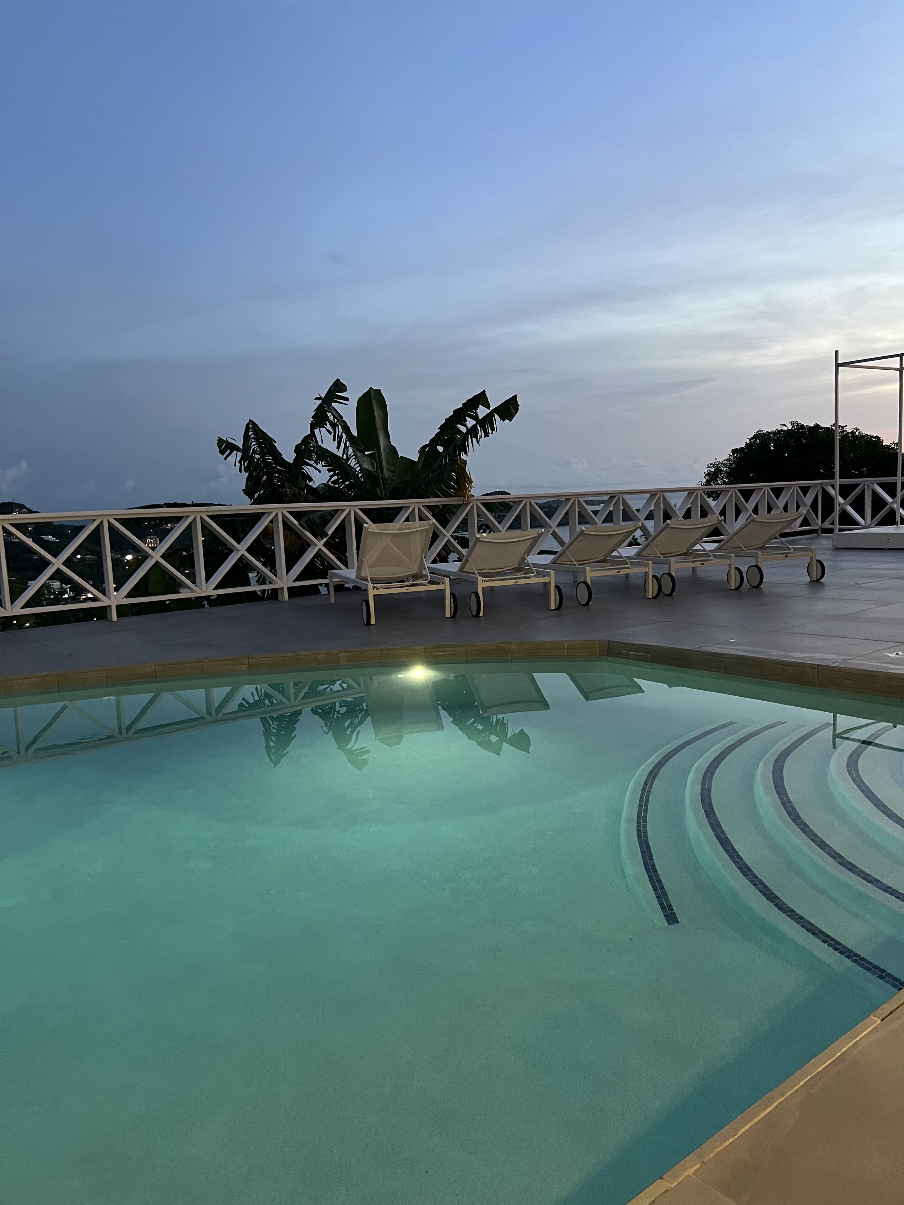 A pool with lounge chairs and a railing.