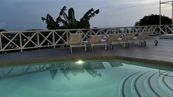 A pool with lounge chairs and a railing.