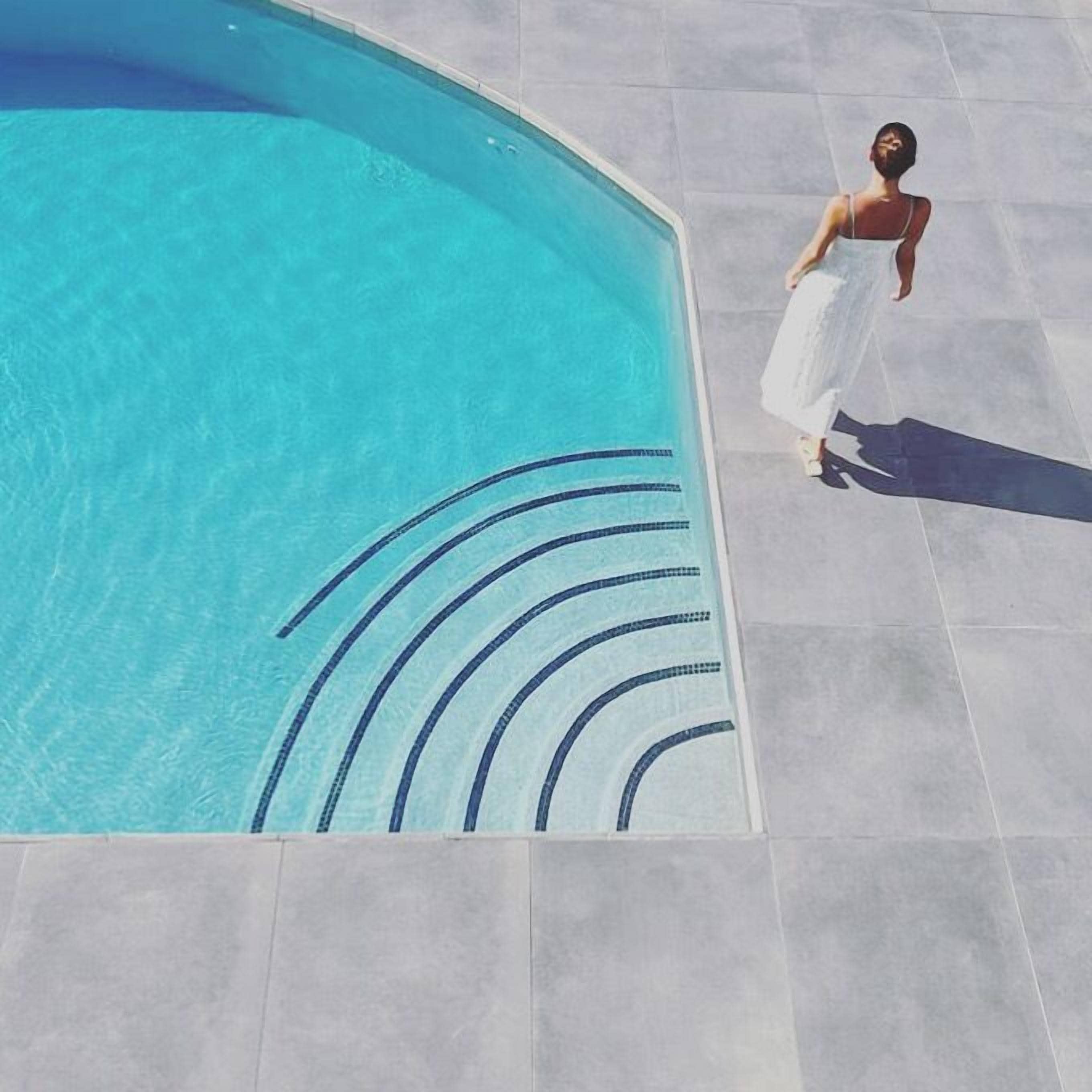 Piscina com água azul cristalina e linhas azuis onduladas no chão.