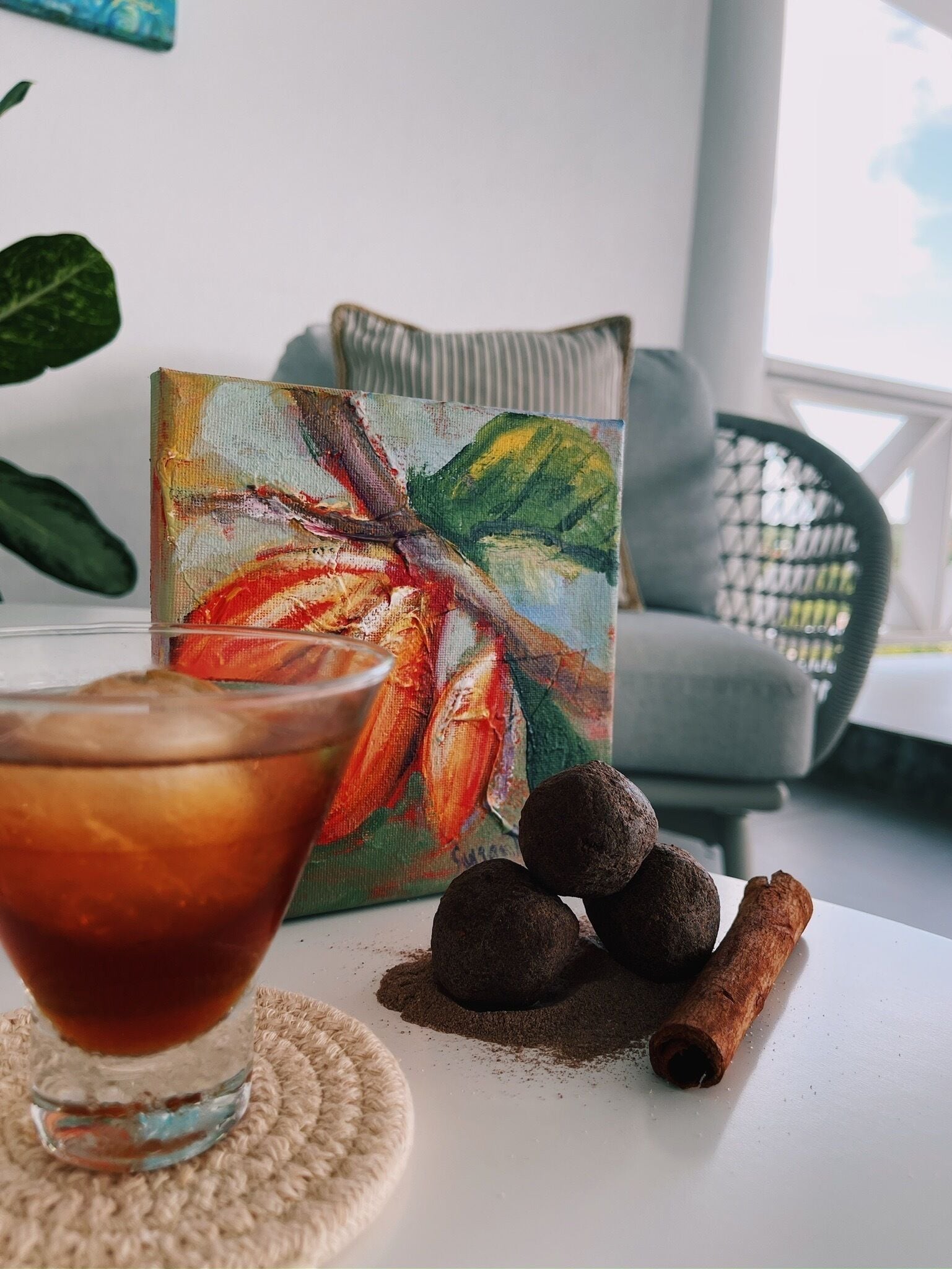 A table with a glass of iced coffee, a box of chocolates, and cinnamon sticks.